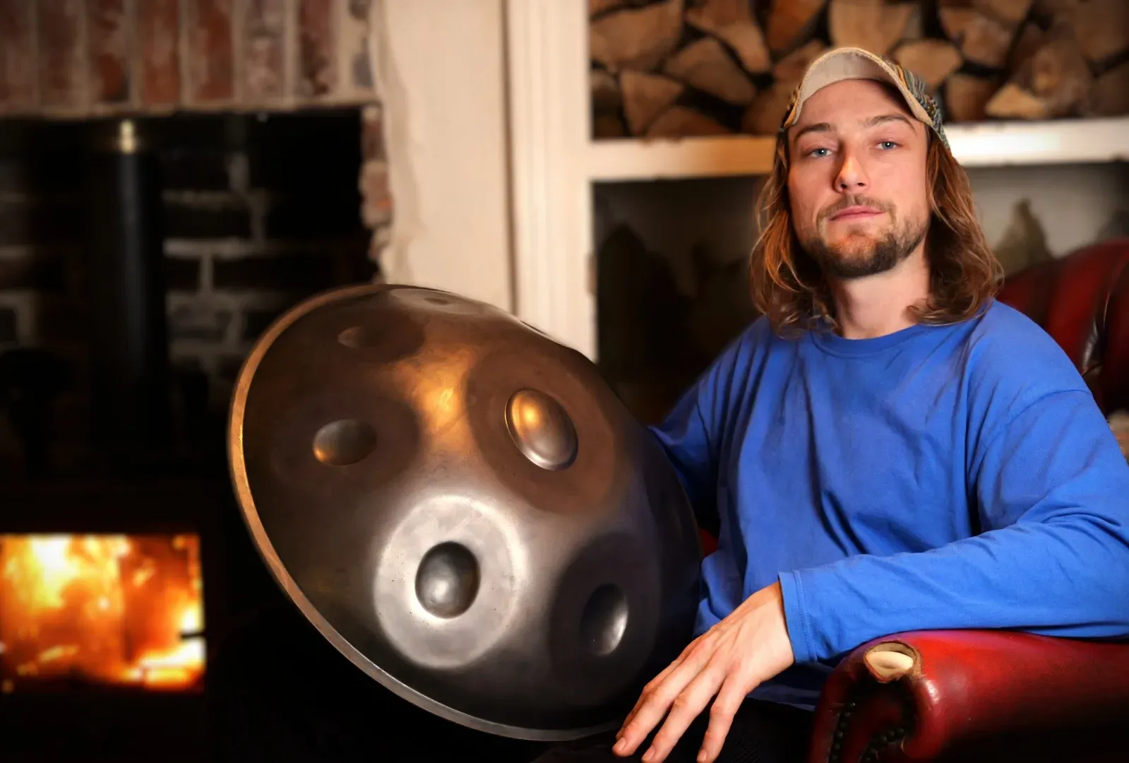 Joe Jordan holding a handpan by a fireside